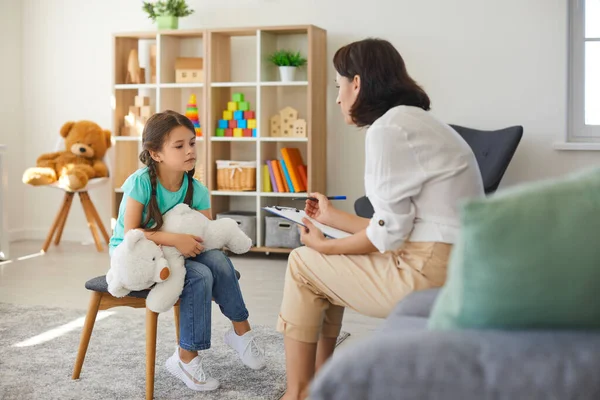 Klein meisje delen haar zorgen met ondersteunende kind psycholoog tijdens therapie sessie in — Stockfoto