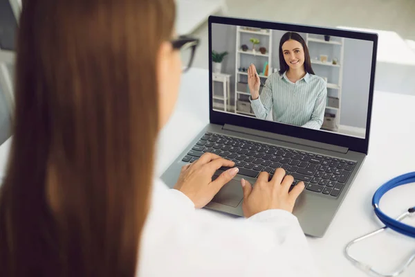 Video oproep naar arts online. Vrouw patiënt groet arts van de medische kliniek in laptop monitor videogesprek thuis. — Stockfoto