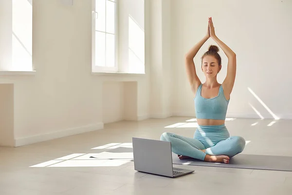 Жіночий тренер йоги, що показує Асану перед ноутбуком під час онлайн-відео уроку з клієнтом — стокове фото