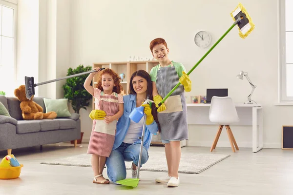 Mãe feliz e crianças com esfregões de chão e dustpan sorrindo e olhando para a câmera depois de um grande clear-out — Fotografia de Stock