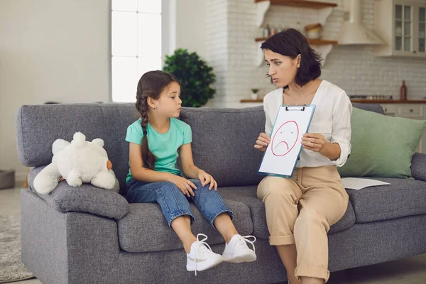 Gadis kecil melihat gambar yang ditunjukkan kepadanya oleh psikolog anak di resepsi nya. — Stok Foto