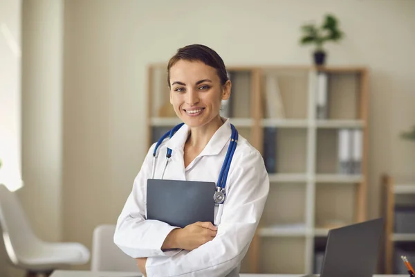 Young smiling doctor therapist standing and looking at camera in medical clinic