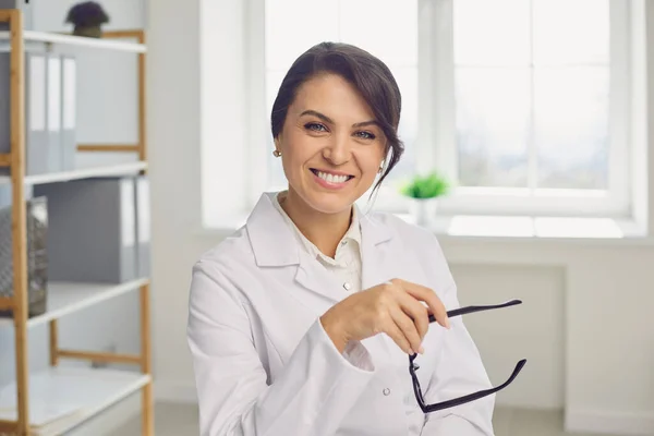 Usmívající se žena lékař při pohledu do kamery během on-line konzultace na lékařské klinice — Stock fotografie