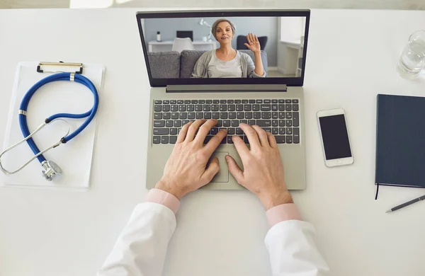 Online doctor. Senior woman waving hand on laptop screen.