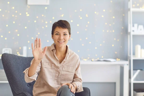 Smiling girl blogger greets and waves her hand starting video recording on her blog. Video conference online. — Stock Photo, Image