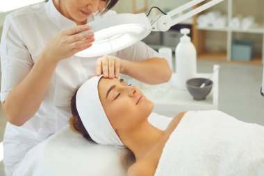 Modern güzellik salonunda profesyonel cilt bakımının keyfini çıkaran rahat genç bir kadın.