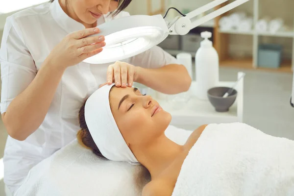 Mujer joven y relajada disfrutando de procedimientos profesionales de cuidado de la piel en el salón de belleza moderno — Foto de Stock