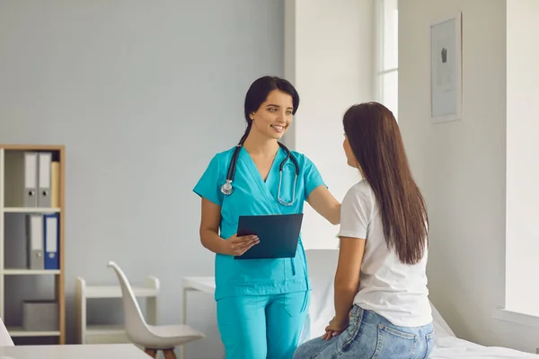 Joven médico sonriente calmando paciente sentada mujer durante la consulta en la clínica médica —  Fotos de Stock