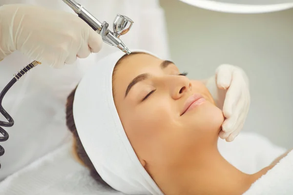 Smiling womans face getting oxygen therapy or jet peeling from cosmetologist — Stock Photo, Image