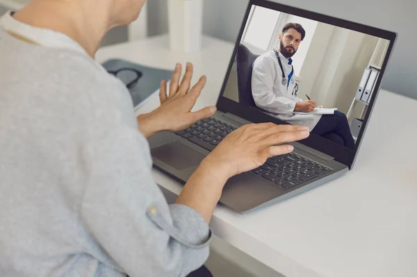 Жінка-пацієнт спілкується з впевненим чоловіком лікарем-терапевтом під час відеозапису на ноутбуці — стокове фото