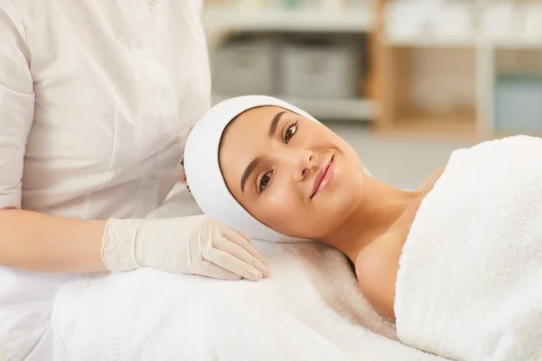 Посміхаючись молода жінка дивиться на камеру після процедури масажу обличчя — стокове фото