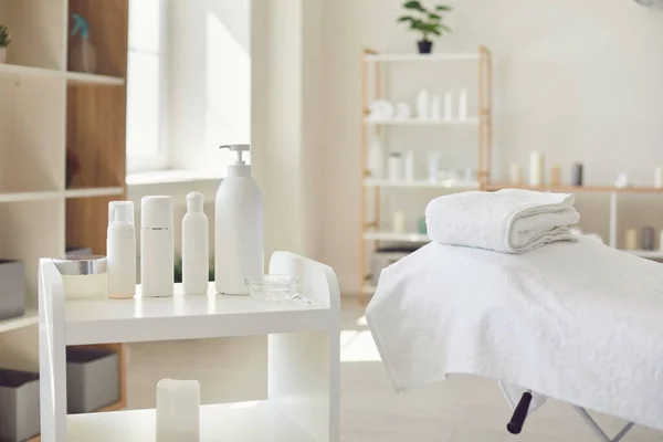 Spa rum eller skönhetssalong med uppsättning ekologiska hudvårdsprodukter och tom säng med färska handdukar — Stockfoto