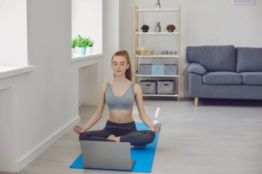 Evde yoga dersinde meditasyon yapan genç bir kız.