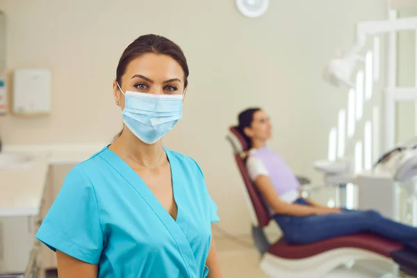 Woman doctor dentist in medical uniform and mask standing and looking at camera in clinic — Stock Photo, Image