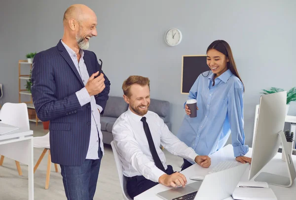 Positive company workers talking, laughing, enjoying conversation during coffee break at work