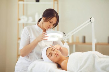 Modern güzellik salonunda profesyonel cilt bakımının keyfini çıkaran rahat genç bir kadın.