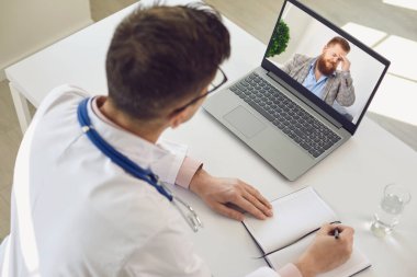 Hastanedeki doktor modern dizüstü bilgisayar kullanarak hastaya online danışmanlık yapıyor.