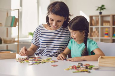 Mutlu anne ve gülümseyen kız evde oturup bulmaca topluyor.