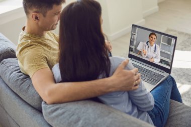 Doktorlarla çevrimiçi danışmanlık. Çift odadaki dizüstü bilgisayarını kullanarak doktoru internetten dinliyor. Teletıp.