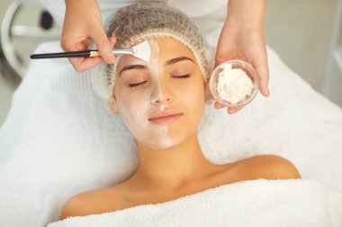 Dermatolog cilt bakımı sırasında kadınların yüzüne nemlendirici maske takıyor.