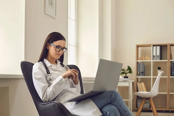 Female doctor consults online a patient through a video call while sitting in the office. — Stock Photo, Image