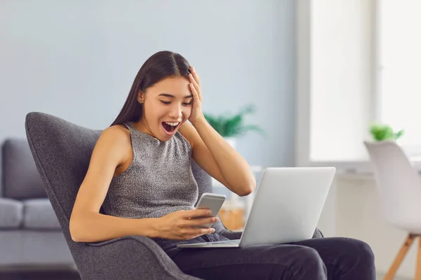 Super happy young girl receiving social media notification sitting in armchair at home — Stock Photo, Image