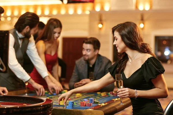 Een jonge vrouw zit aan tafel roulette spelen poker in een casino. — Stockfoto