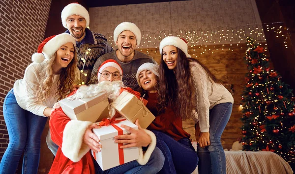 Amigos em chapéus Santas mudar presentes na festa de Natal — Fotografia de Stock