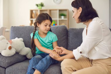 Mother sitting with daughter, holding her hands, talking to her and teaching her something clipart