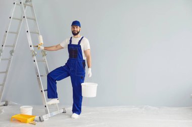 Gülümseyen ressam boya silindiri ve kovayla kamerayı tamir etmek için bekliyor.