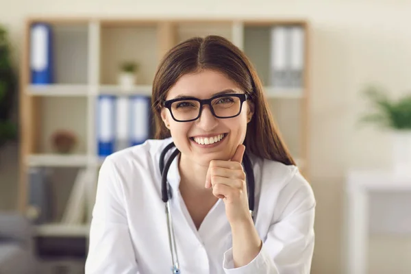 Ritratto di giovane medico donna amichevole alla scrivania in ufficio sorridente al paziente — Foto Stock