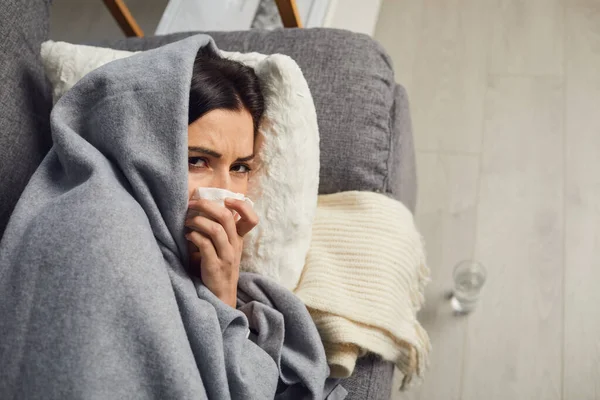 Above view of young girl lying on sofa, covered with warm plaid, suffering from bad cold or infection at home — Stock Photo, Image