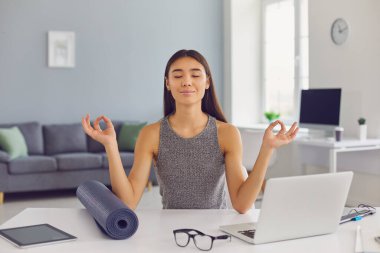 Rahat iş kadını ofisinde masasında oturuyor işe ara veriyor ve meditasyon yapıyor.