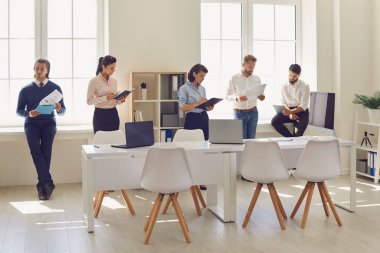 Şirket yöneticisini beklerken finansal raporları okumakla meşgul ciddi çalışanlar.