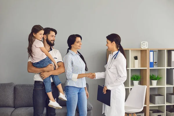 Família feliz dizendo adeus à mulher médico e apertando as mãos após visita bem sucedida na clínica médica — Fotografia de Stock