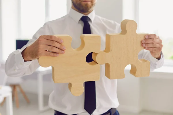 Обрезанный бизнесмен или менеджер компании в офисной одежде, соединяющий два кусочка головоломки — стоковое фото