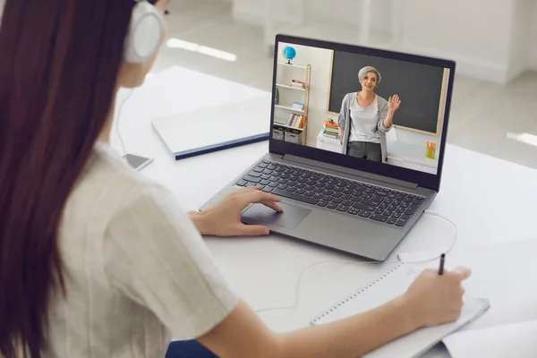 Lärande utbildning kursföreläsning på nätet. Flicka student i hörlurar lyssnar på läraren videochatt ansökan på distans hemma — Stockfoto