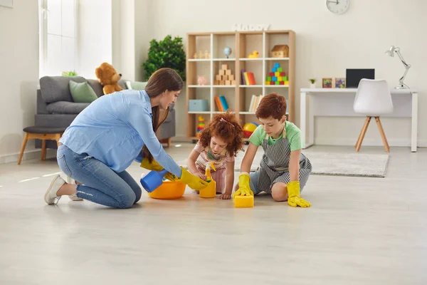 Szczęśliwa rodzina sprząta pokój rękawiczkami. Matka, syn i córka sprzątają dom.. — Zdjęcie stockowe