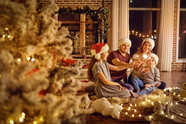 Familie mit Wunderkerzen in der Hand in einem Raum zu Weihnachten. — Stockfoto