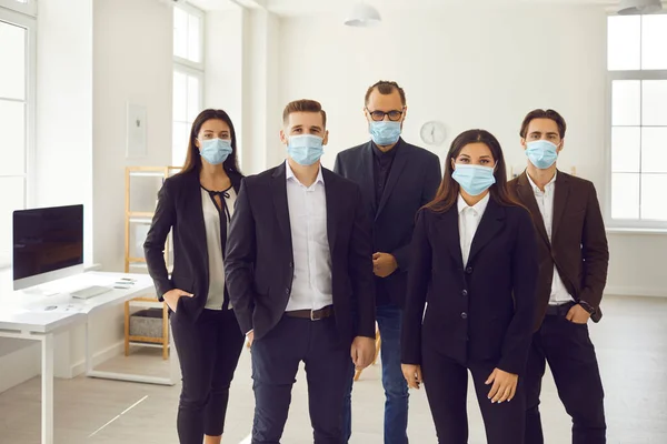 Group of young company workers care about customers and wear medical face masks at work — Stock Photo, Image