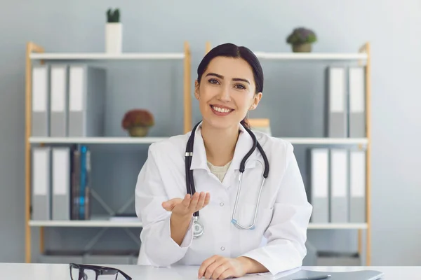 Sorridente medico femminile che dà consulenza medica al paziente online dalla clinica. Giovani GP che comunicano al cliente sul web — Foto Stock