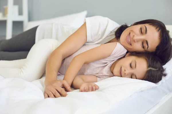 Glücklich entspannte Mutter und Tochter kuscheln am Wochenende auf weichem Bett im ruhigen Schlafzimmer — Stockfoto