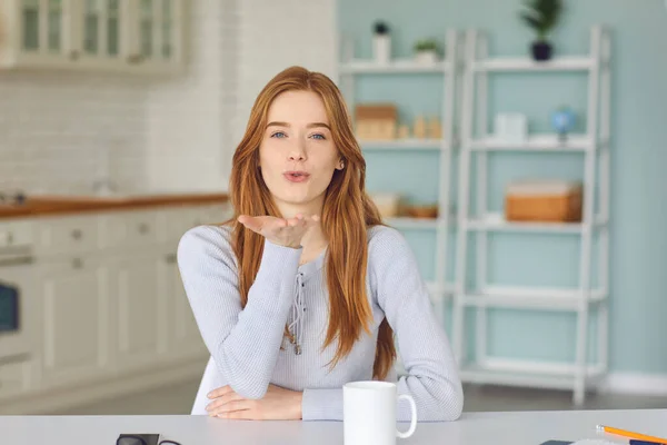 Positive woman looking at camera and sending air kiss to somebody online — Stock Photo, Image