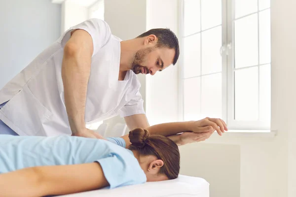 Ung specialist gör medicinsk massage till kvinnlig patient i modern vårdcentral — Stockfoto