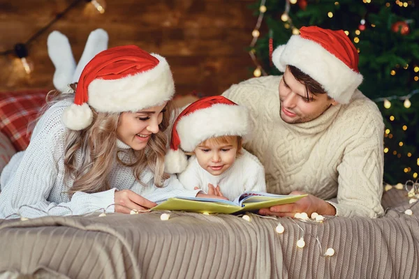 Ευτυχισμένη οικογένεια που διαβάζει ένα βιβλίο τα Χριστούγεννα. — Φωτογραφία Αρχείου