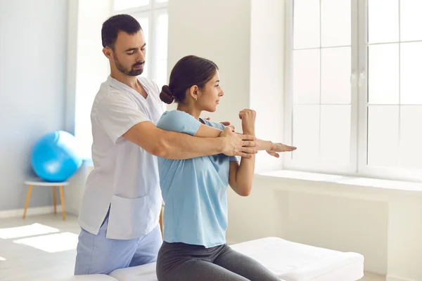 Physiotherapist and patient working on arm injury, doing medical exercise, stretching muscles