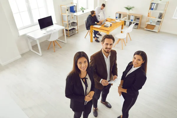 Socios empresariales jóvenes aspirantes en ropa formal mirando a la cámara durante la reunión en un espacio de trabajo moderno —  Fotos de Stock