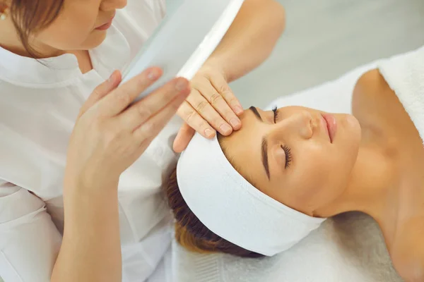 Cosmetoloog controleert de elasticiteit van de huid en doet onderzoek bij jonge ontspannende vrouwen — Stockfoto