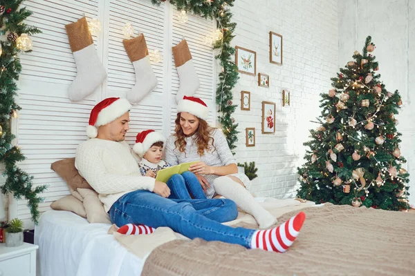 Familie liest ein Büchlein in einem Haus mit Weihnachtsbaum. — Stockfoto