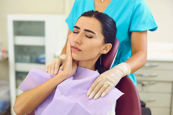 Mujer joven está sentada en una silla de dentista y sufre de dolor de muelas severo. —  Fotos de Stock